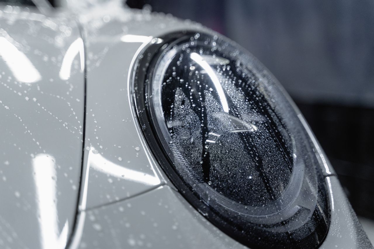 our-story-02 A detailed shot of a car headlight covered in water droplets, showcasing automotive design.